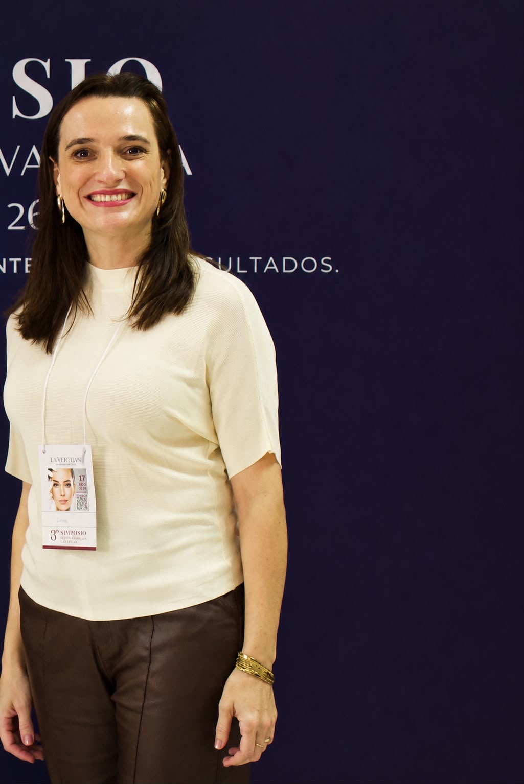 Liana Vertuan com crachá, em evento da La Vertuan.